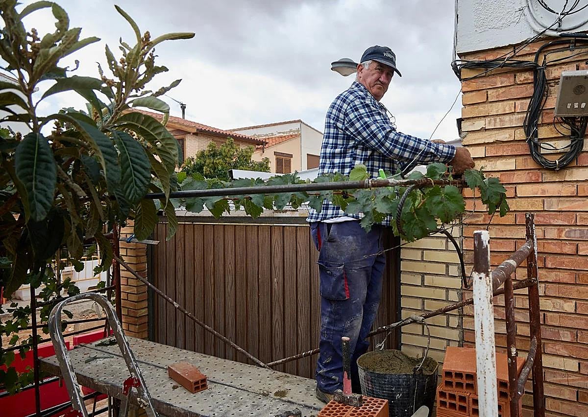 Imagen secundaria 1 - Pedro señala la altura a la que llegó el agua en el interior de su vivienda. David refuerza el pórtico del garaje de una casa. Destrozos en el cauce del Magro todavía sin reparar.