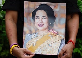 Una mujer sostiene un retrato de la reina emérita tailandesa en Bangkok.