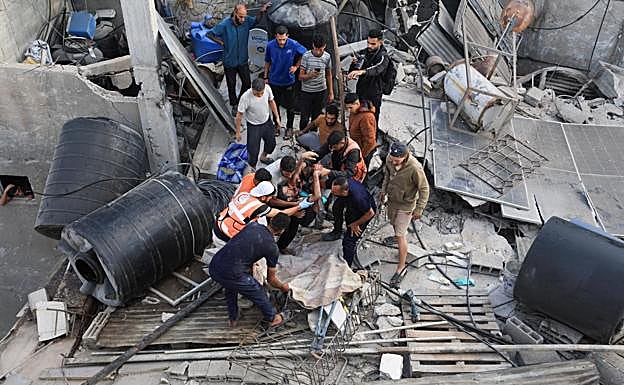 Los servicios de emergencia rescatan el cuerpo de una de las víctimas mortales en los bombardeos sobre Gaza.