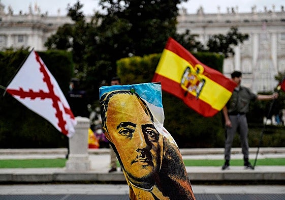 Manifestantes agitan banderas tras una pancarta con la imagen del dictador español Francisco Franco.