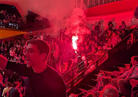 Un activista prende una bengala en la sala de conciertos de la Filarmónica de París.