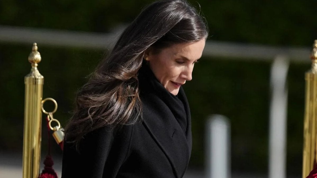 Letizia arrasa con un total look negro con abrigo envolvente tipo batín en el aeropuerto, antes de embarcar para China