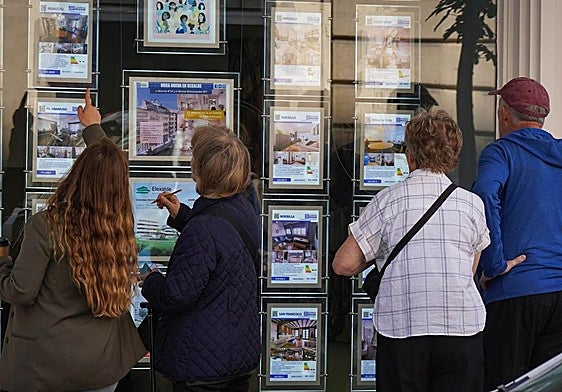 Varias personas mirando anuncios de viviendas.