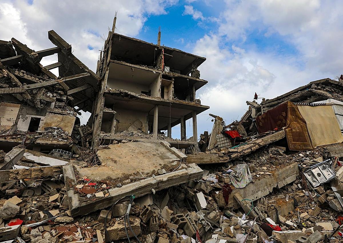 Imagen secundaria 1 - Una mujer con un crío en brazos entre los restos de la guerra en Ciudad de Gaza; edificios reducidos a escombros en el barrio de Radwan, en el norte de la Franja; un niño trata de empujar el agua tras las lluvias sobre el enclave. 
