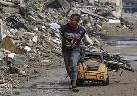 Un chico arrastra un carro con trozos de metal por una calle arrasada por los bombardeos en Ciudad de Gaza.