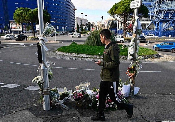 Un peatón pasa junto a un memorial improvisado en el lugar donde Mehdi Kessaci fue asesinado en Marsella.