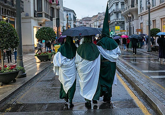 Nazarenos se protegen de la lluvia en la Semana Santa en Granada.