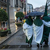 Nazarenos se protegen de la lluvia en la Semana Santa en Granada.