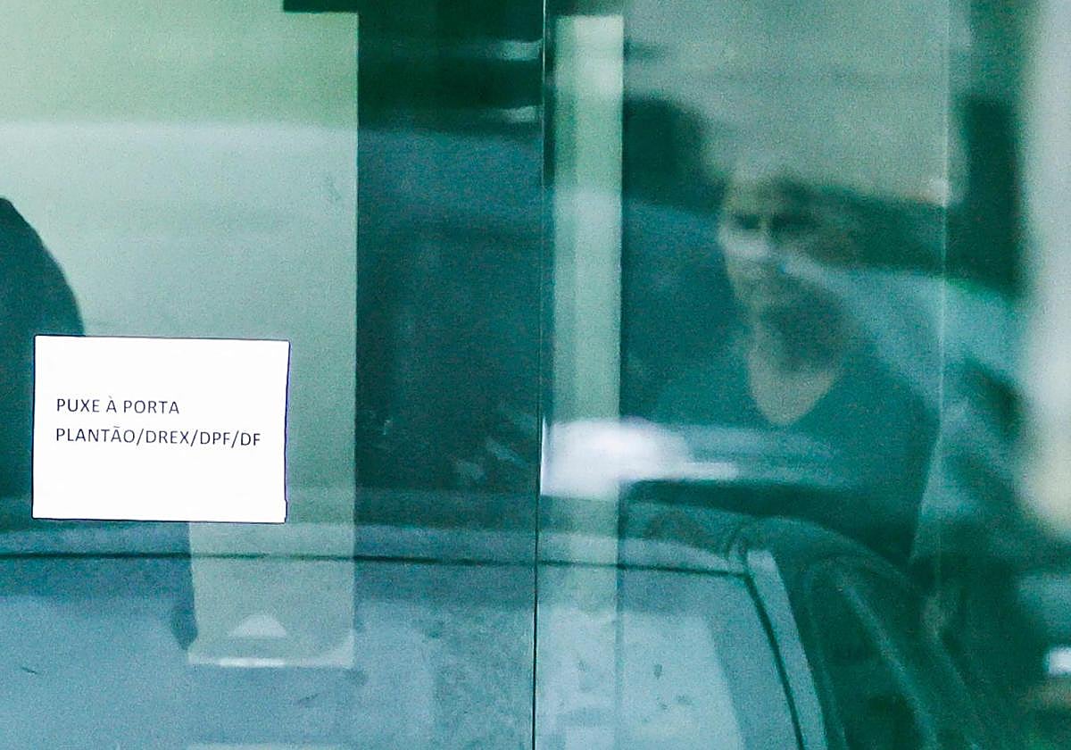 Bolsonaro es visto a través de una puerta acristalada de la sede de la Policía Federal de Brasilia, donde se encuentra recluido desde el sábado.