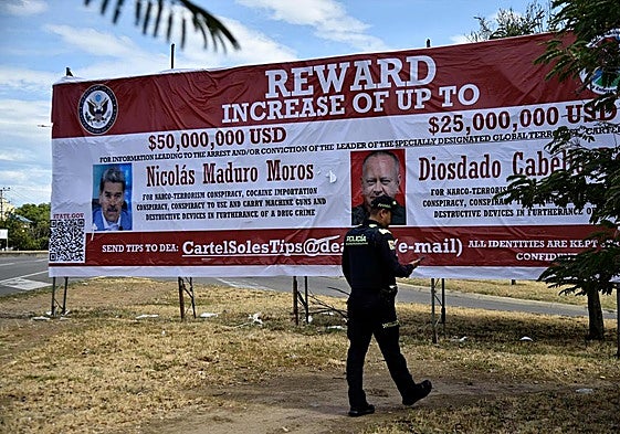 Un policía colombiano camina frente a un cartel que ofrece una recompensa millonaria por la detención de Nicolás Maduro y Diosdado Cabello, a quienes EE UU acusa de liderar el Cártel de los Soles.