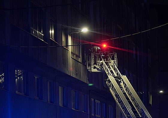 Los bomberos tratan de acceder a una de las viviendas del edificio de A Coruña que sufrió un incendio este jueves.