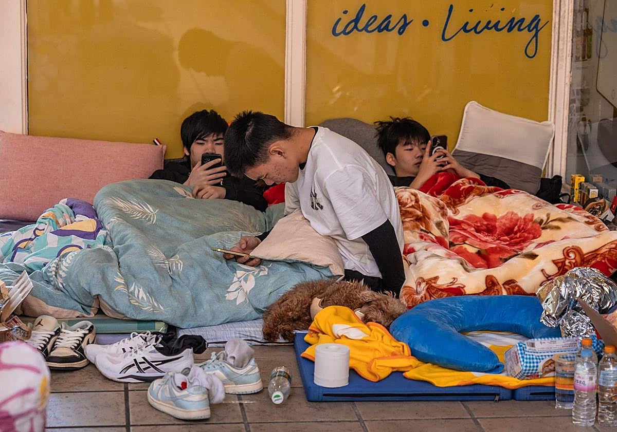 Imagen principal - Varios residentes en las torres calcinadas pasan la noche en un centro comerciales: decenas de bolsas con artículos de primera necesidad para los damnificados; rescatistas portan varias mascotas. 