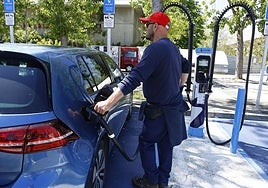 Un hombre cargando su coche eléctrico.