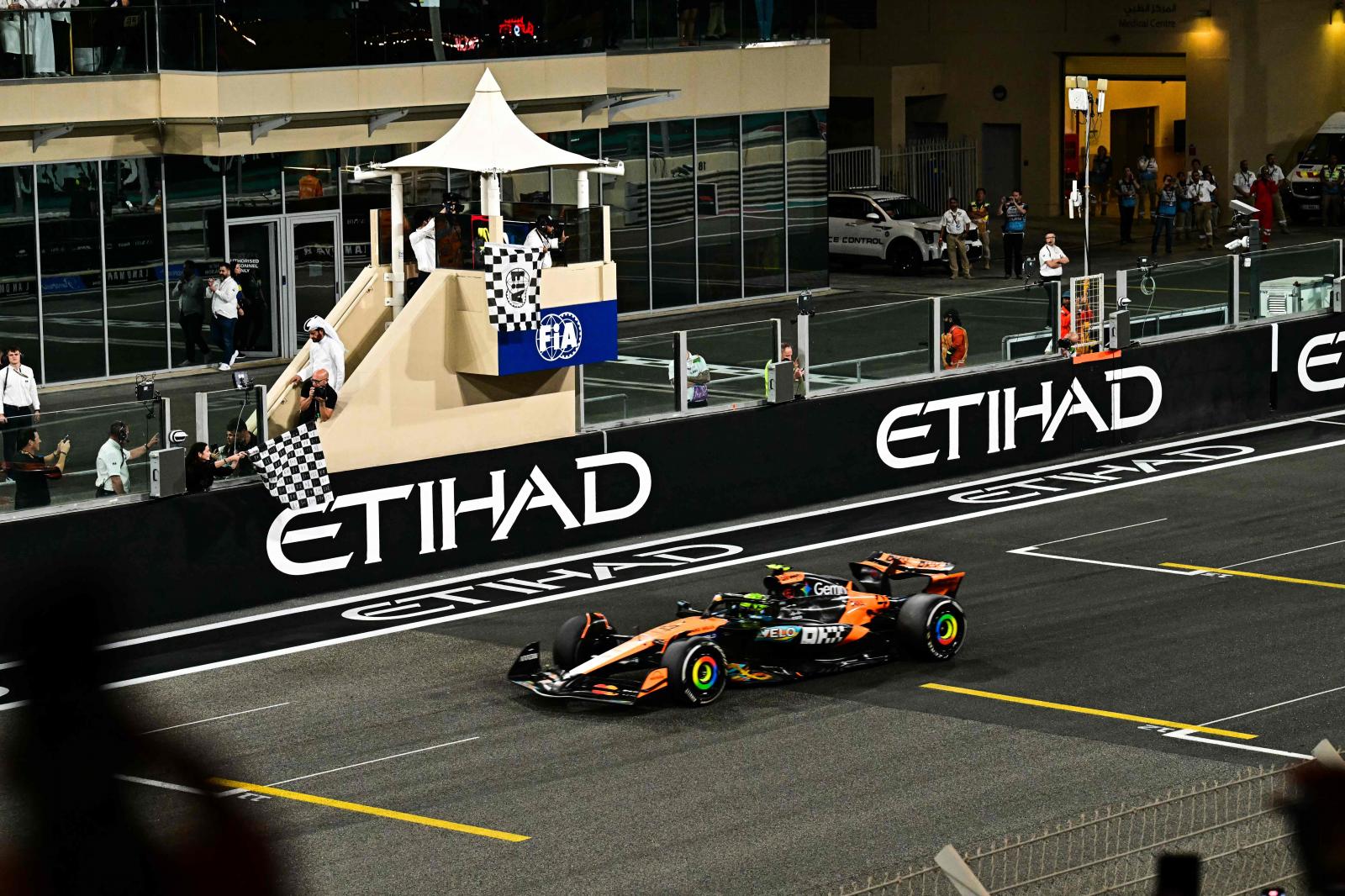 La bandera a cuadros ondea al paso de Lando Norris por la línea de meta del GP de Abu Dabi.