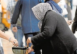Una mujer mayor pide ayuda en la calle de una ciudad española.
