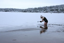 La nadadora sobre hielo Justina Pliuskeviciute usa un piolet para romper el hielo en Loch Morlich, en Aviemore, Escocia