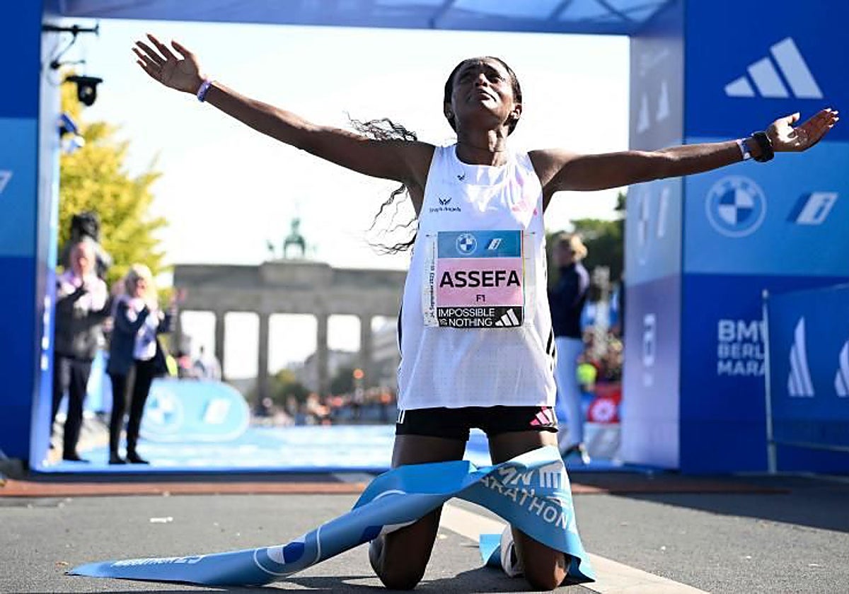 Tigist Assefa llora de rodillas tras cruzar la meta del maratón de Berlín.