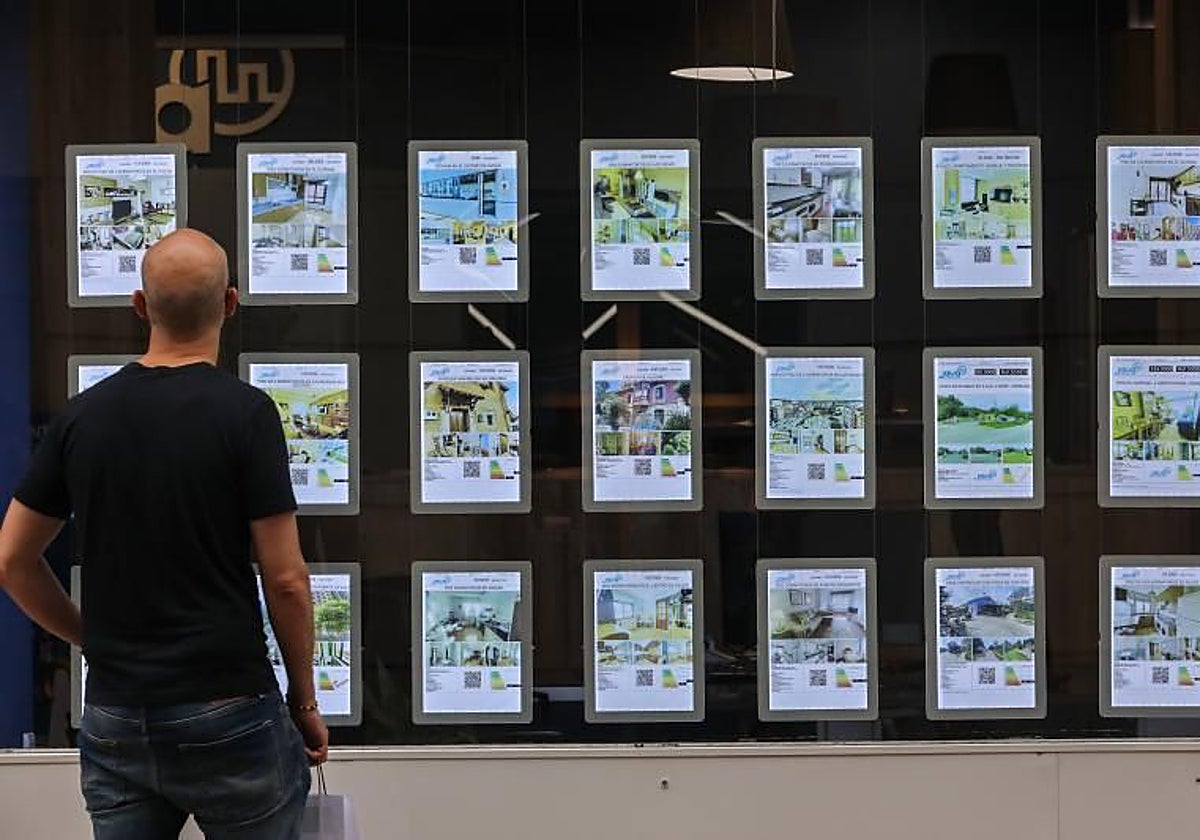 Un hombre contempla el escaparate de una inmobiliaria.