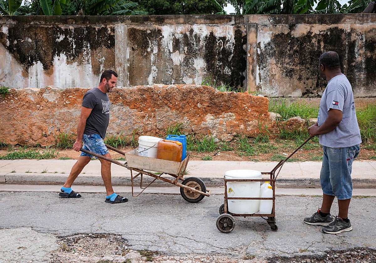 Dos cubanos acarrean agua en La Habana.