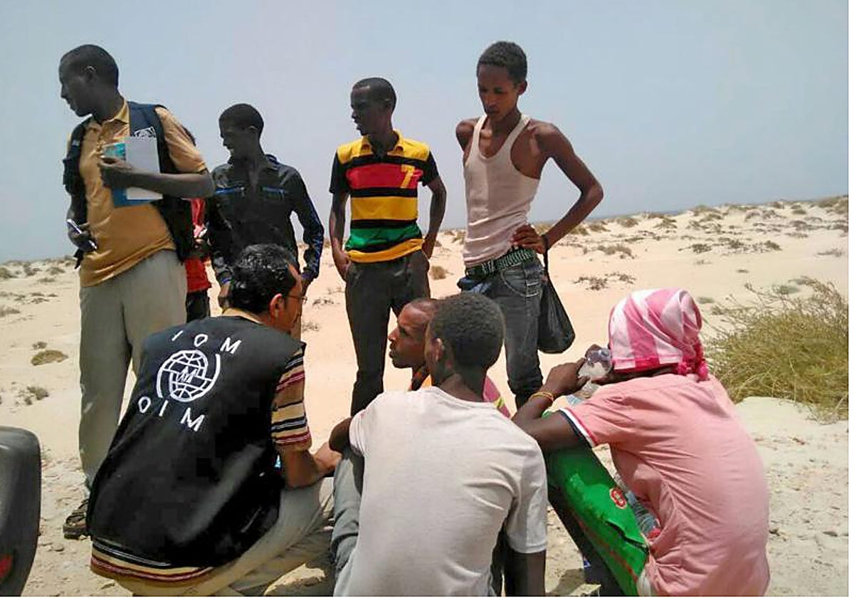 Un trabajador de la OIM trata con un grupo de inmigrantes etiopes y somalíes en una playa de Yemen.