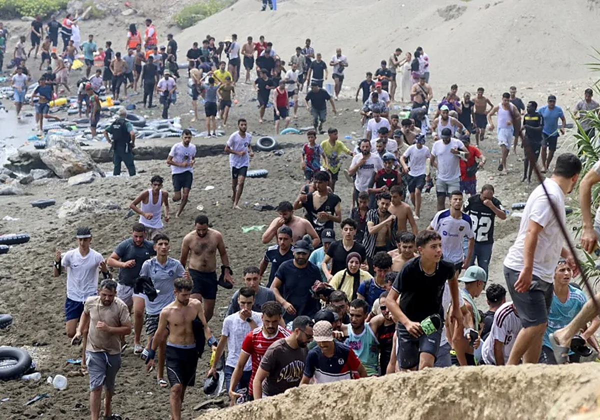 Decenas de marroquíes entran en Ceuta a través del espigón del Tarajal.