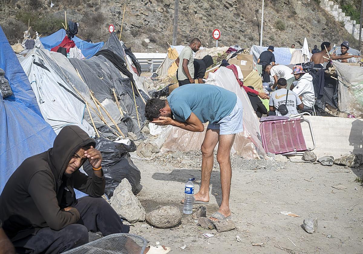 Migrante se asea, en la playa de Trampolín.