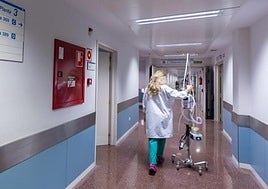 Una sanitaria empuja material para el control de la salud de los pacientes por el pasillo de un hospital.