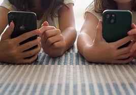 Dos niñas juegan con el teléfono.
