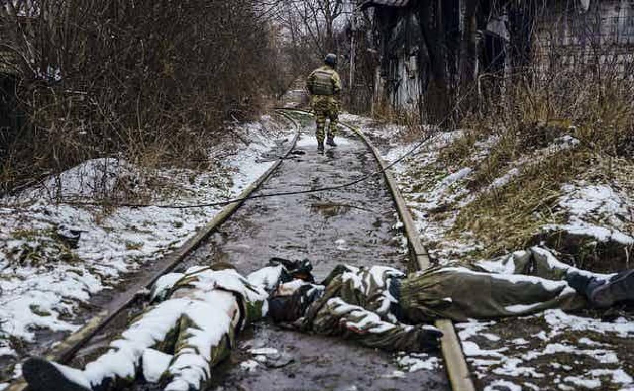 Un soldado ucraniano deambula por una vía férrea junto a los cuerpos de soldados rusos muertos en las afueras de Irpin, Ucrania, el 1 de marzo de 2022.