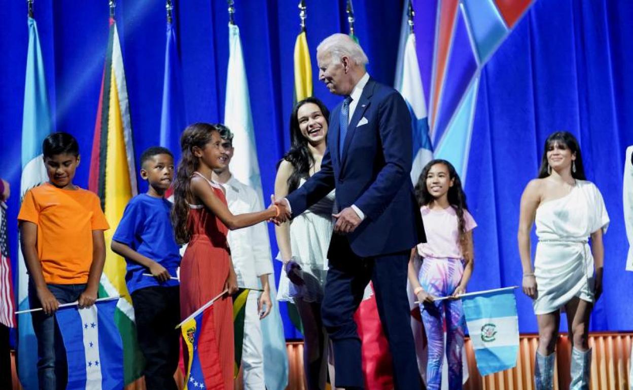 El presidente de EE UU, Joe Biden, saluda a niños en la cumbre.