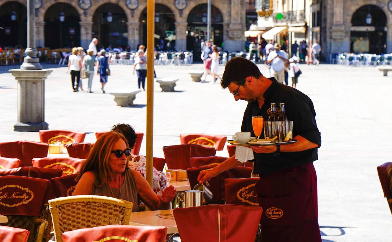 Un camarero atiende a una clienta en una terraza.