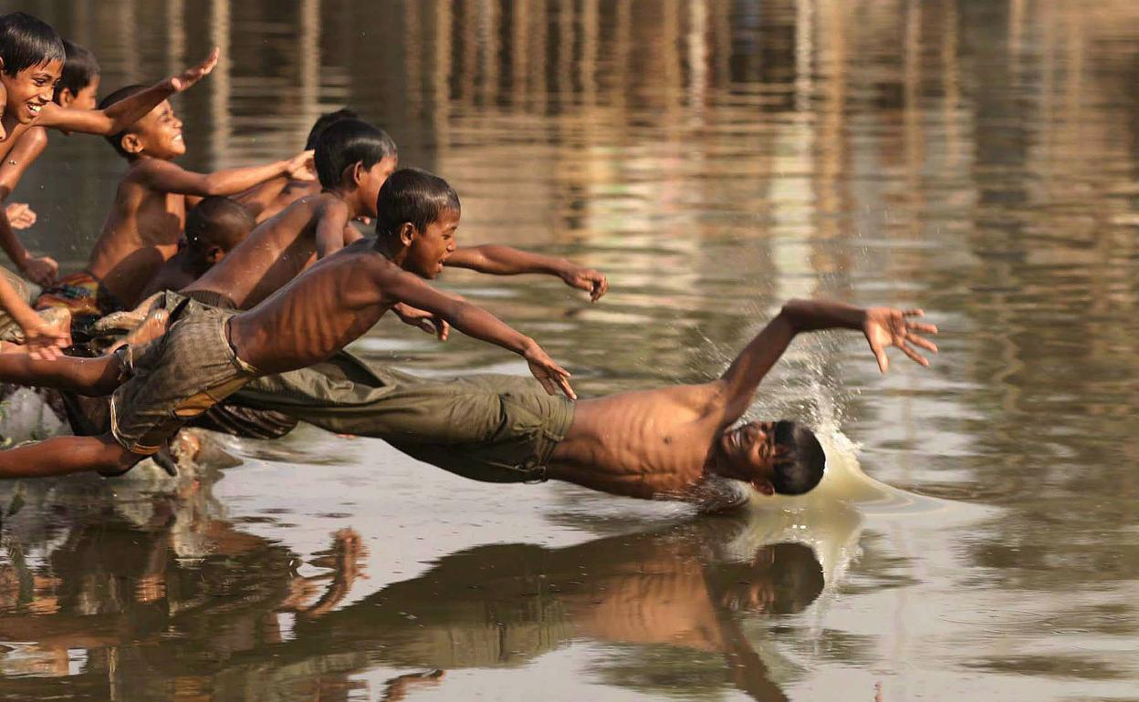 Niños en un río bañándose.