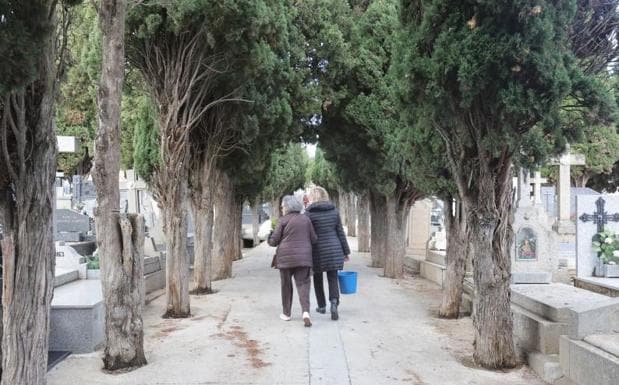 Dos mujeres se dirigen a limpiar una tumba en Salamanca.
