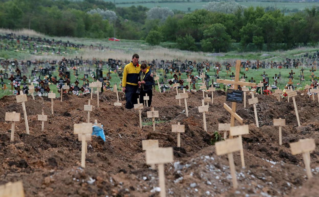 Una pareja visita la tumba de un familiar en un cementerio improvisado de Mariúpol en mayo.