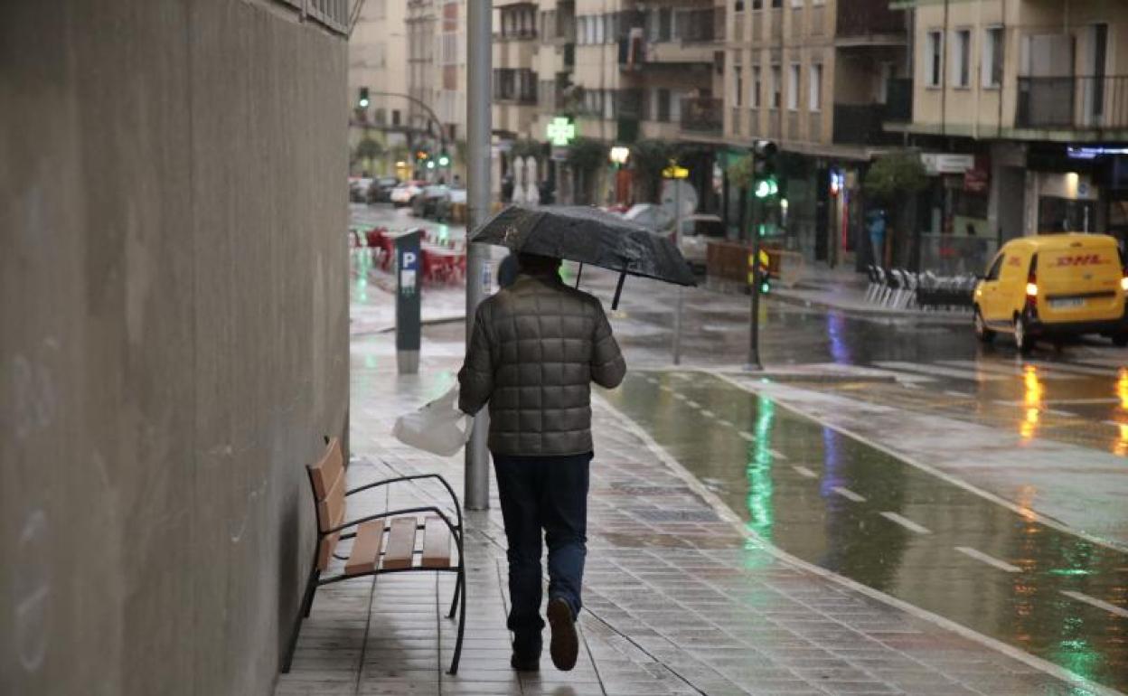 Un ciudadano caminando bajo la lluvia por las calles de Salamanca.