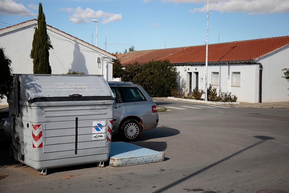 Un colchón abandonado junto a un contenedor.