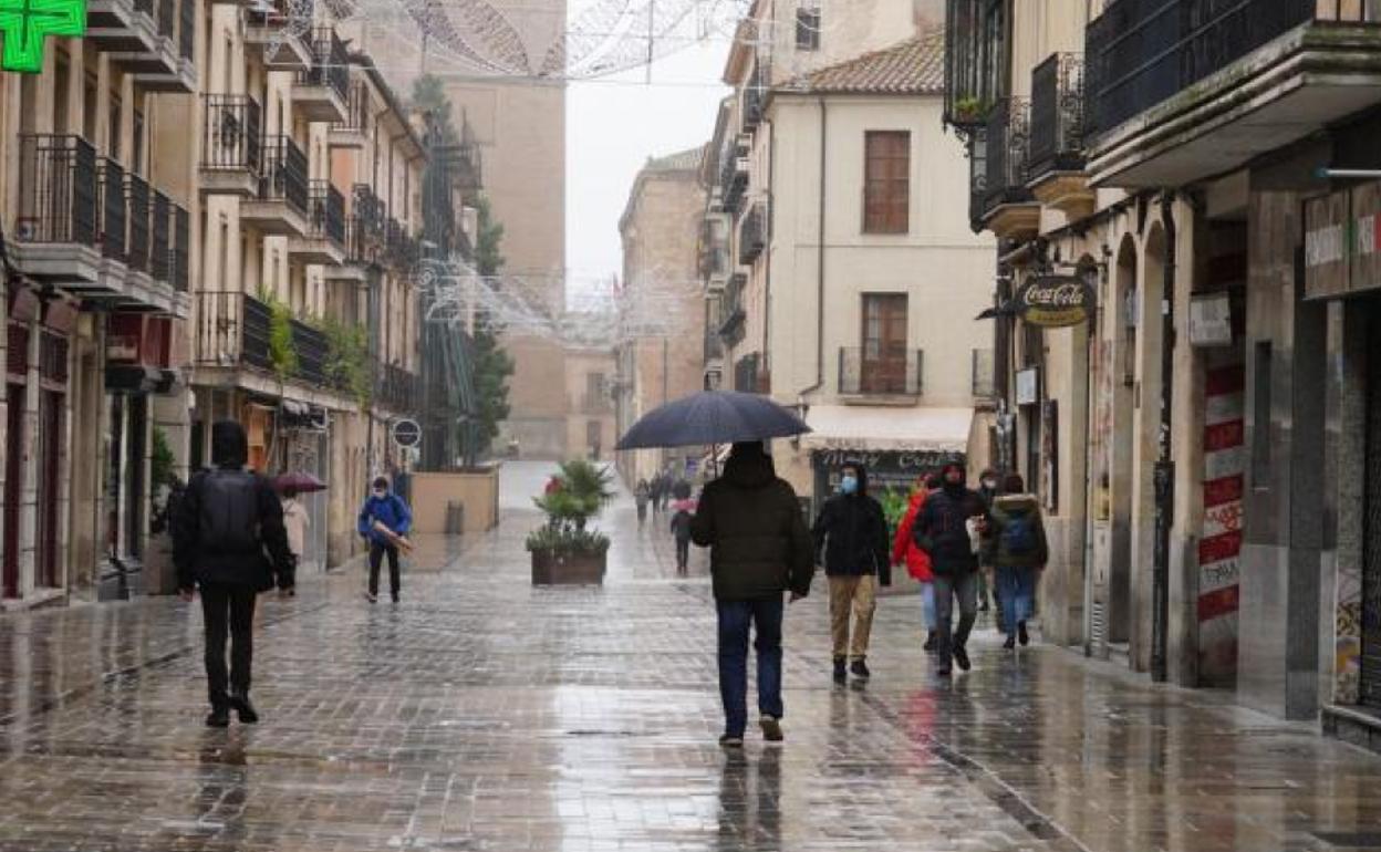 Viandantes bajo la lluvia en la calle Rúa Mayor en el centro de Salamanca.