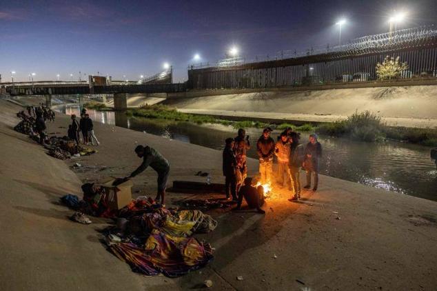 Migrantes pasan la noche a la intemperie, cerca de la valla fronteriza entre Estados Unidos y México, mientras esperan para presentar solicitudes de asilo en El Paso, Texas.