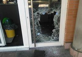 Imagen de archivo de un crital de un local roto con la tapa de ua arqueta.