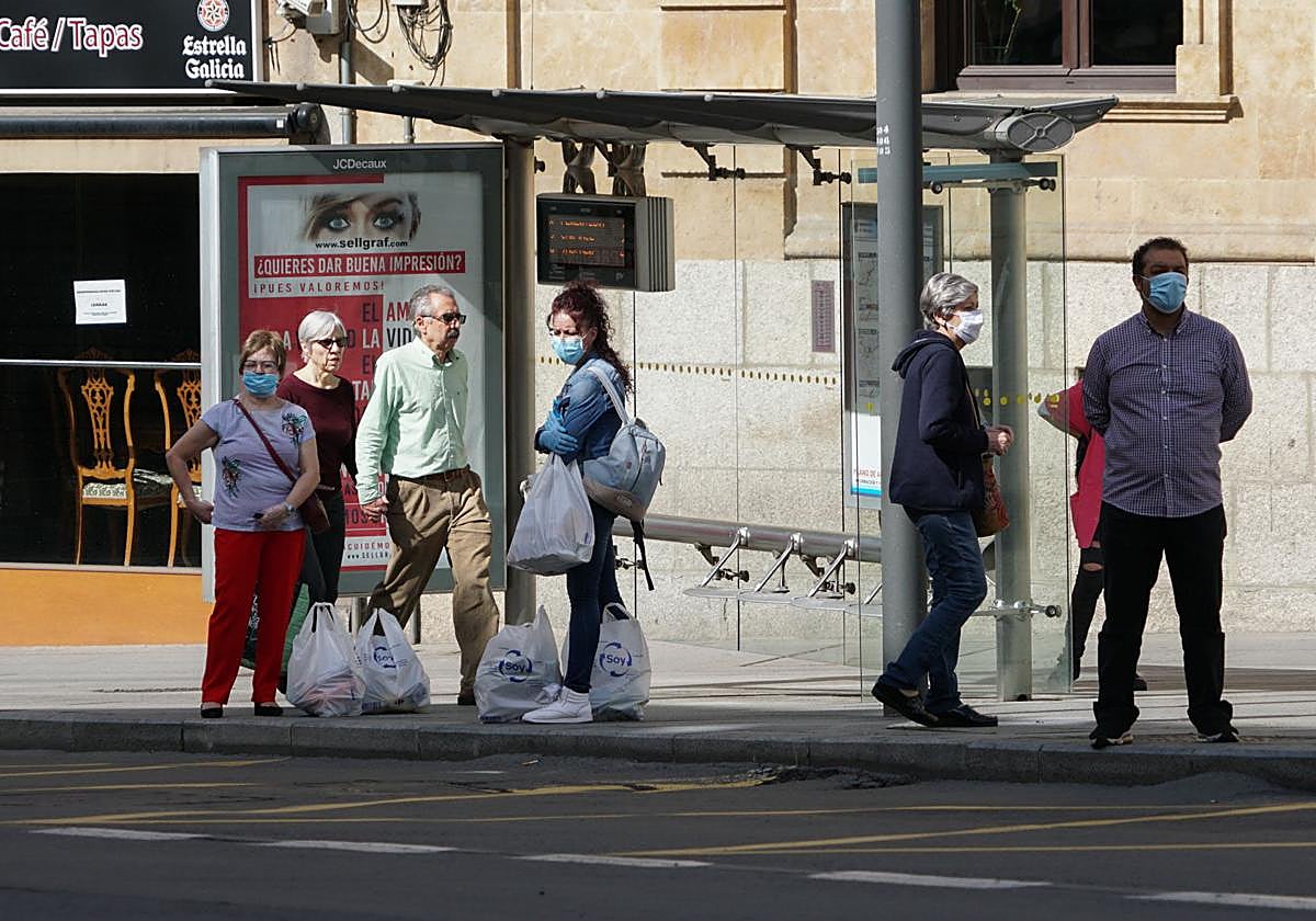 Varias personas esperan la llegada del autobús.