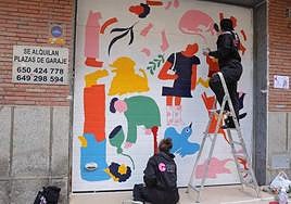 Dos artistas decoran una de las puertas de garaje