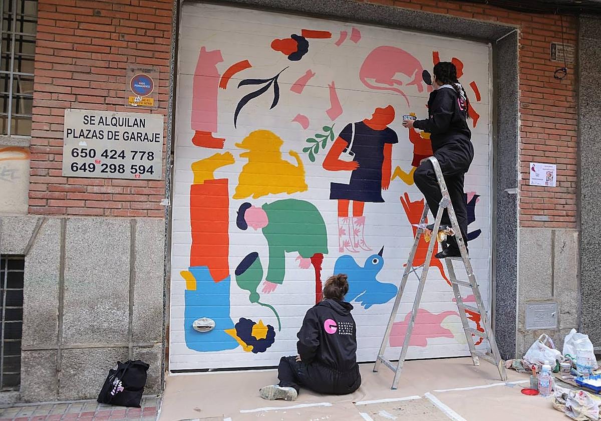 Dos artistas decoran una de las puertas de garaje