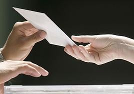 Una persona deposita su voto en una mesa electoral.