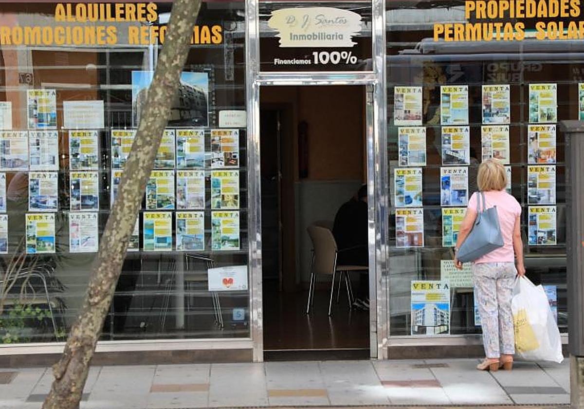 Una persona observa el escaparate de una inmobiliaria.