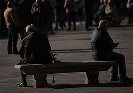 Dos personas, sentadas en un banco de la Plaza Mayor de Salamanca.