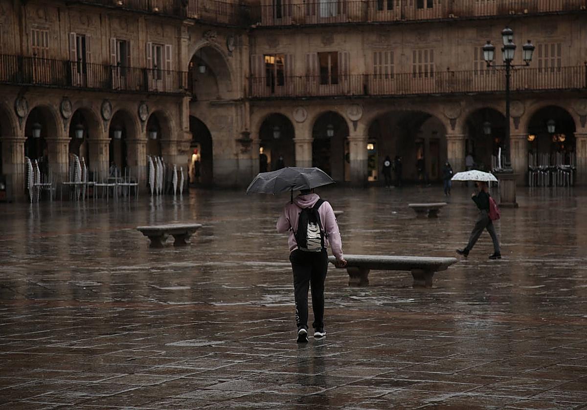 Dos personas caminando bajo la lluvia en la Plaza Mayor de Salamanca.