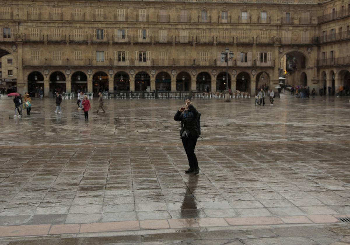 Un ciudadano pasea por la Plaza Mayor de Salamanca mojada por la lluvia.