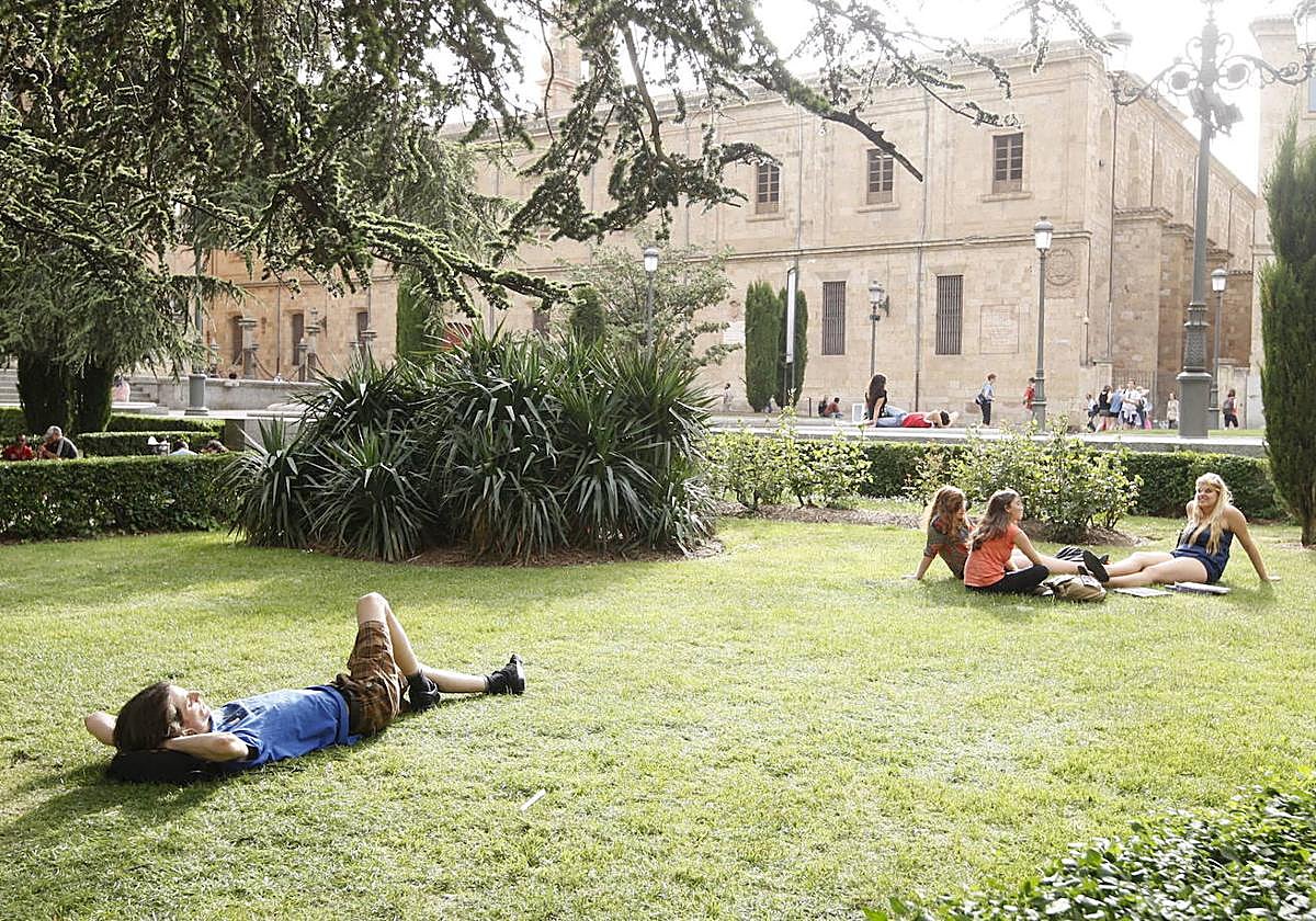 Personas tumbadas en el césped descansando en un día caluroso en Salamanca.