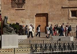 Varios turistas pasean junto a la Casa de las Conchas de Salamanca.