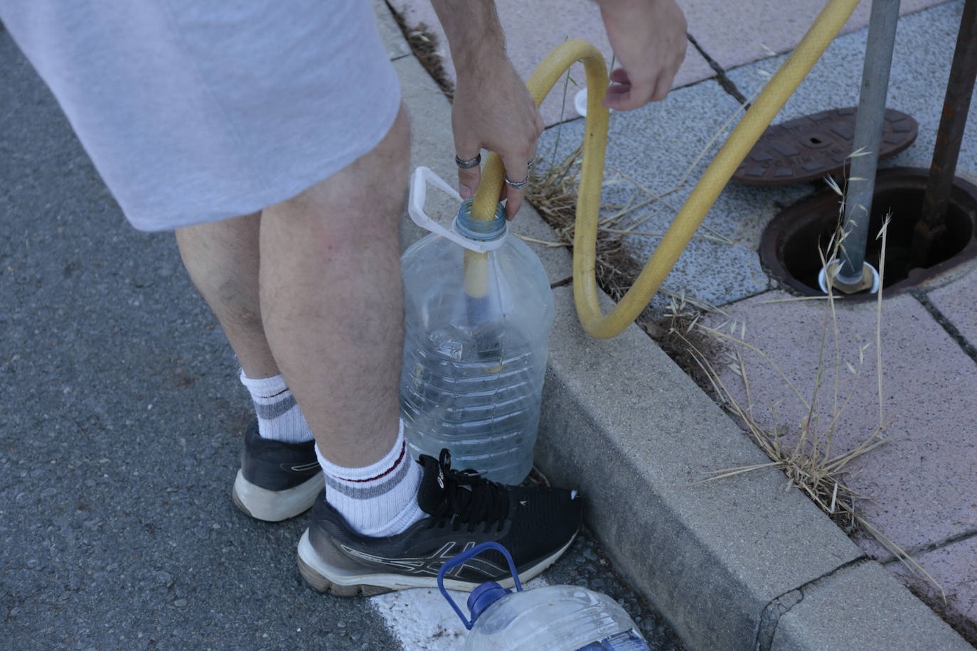 Un hombre rellenando una garrafa de auga.